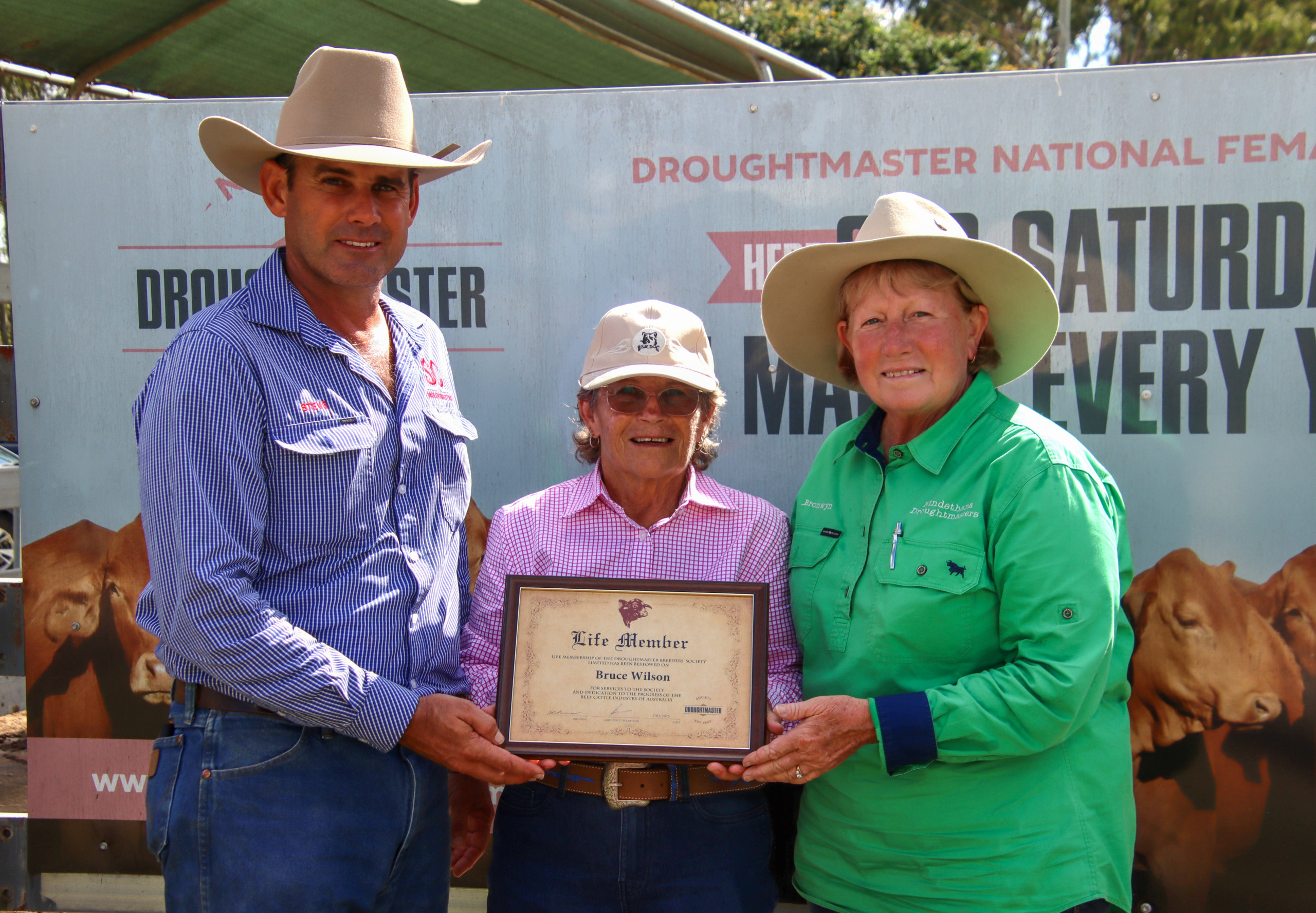 Bruce Wilson’s wife Jeanette Wilson (centre) receives his Life Membership honour, presented by Steven Farmer, Droughtmaster Australia President, and Brownyn Betts, Director South East Zone.